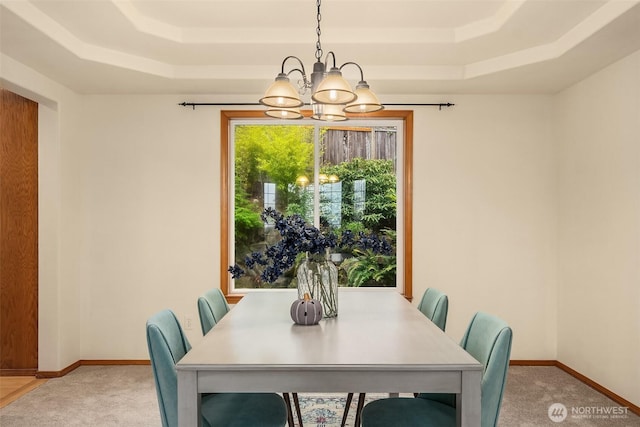 dining area with a tray ceiling, a chandelier, and carpet floors
