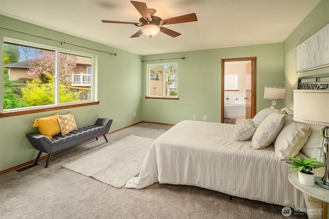 carpeted bedroom with ensuite bathroom, baseboards, and a ceiling fan