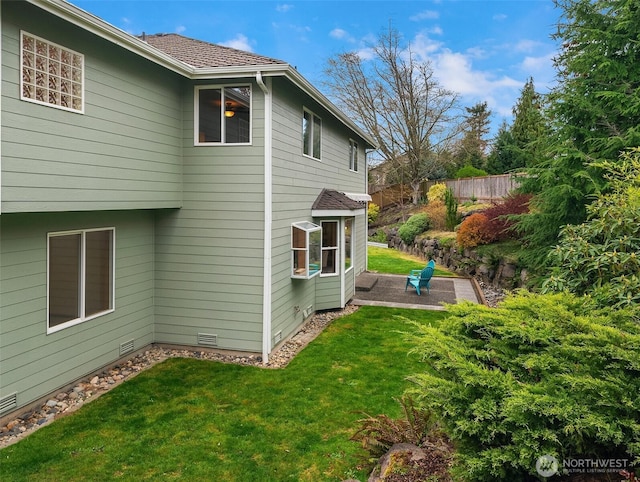 view of side of property featuring a yard, fence, crawl space, and a patio area