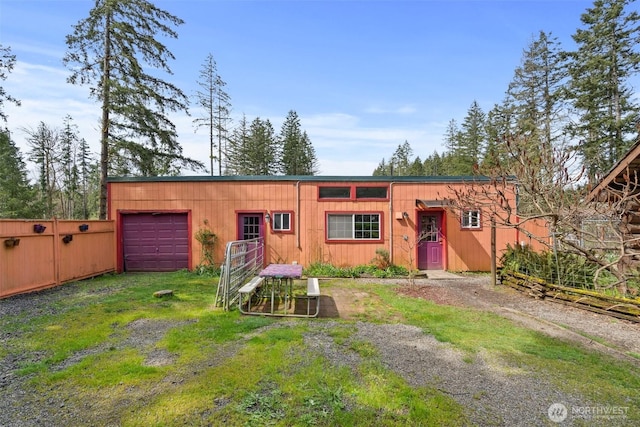 view of front facade featuring an attached garage, driveway, and fence