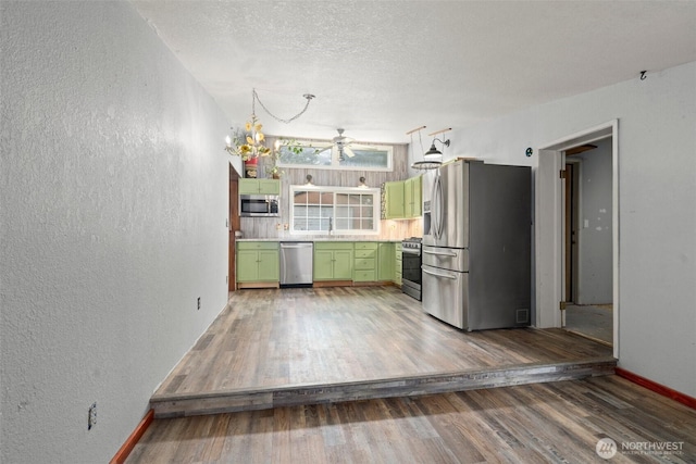 kitchen with light wood-type flooring, a ceiling fan, a textured wall, stainless steel appliances, and green cabinets