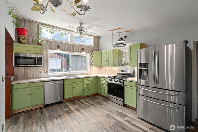 kitchen with green cabinets, light countertops, appliances with stainless steel finishes, a sink, and wood finished floors