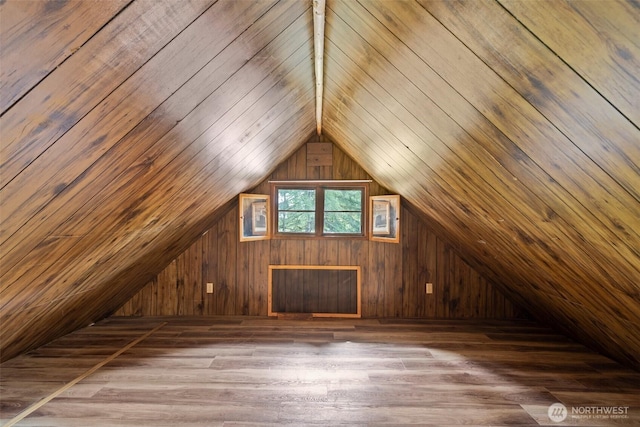 bonus room with wood walls, lofted ceiling, and wood finished floors