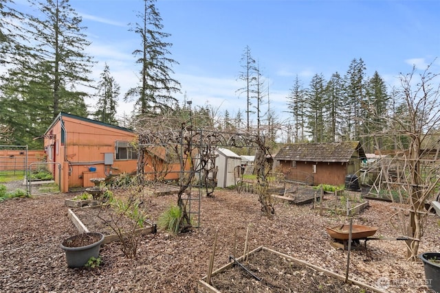 view of yard featuring a vegetable garden, an outdoor structure, a shed, and fence