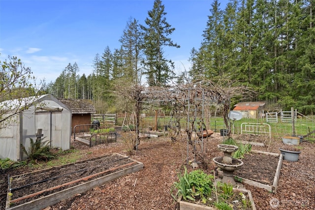 view of yard featuring an outdoor structure, a vegetable garden, fence, and a storage unit