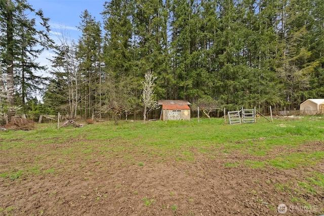 view of yard featuring a storage shed, fence, and an outdoor structure