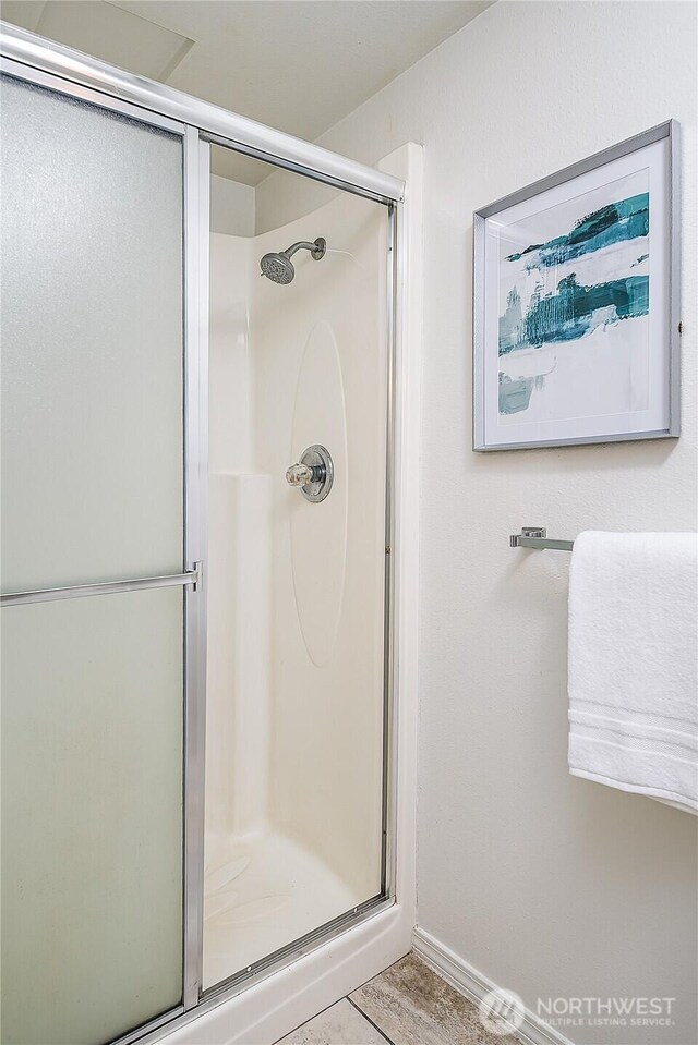 full bathroom featuring a stall shower and baseboards