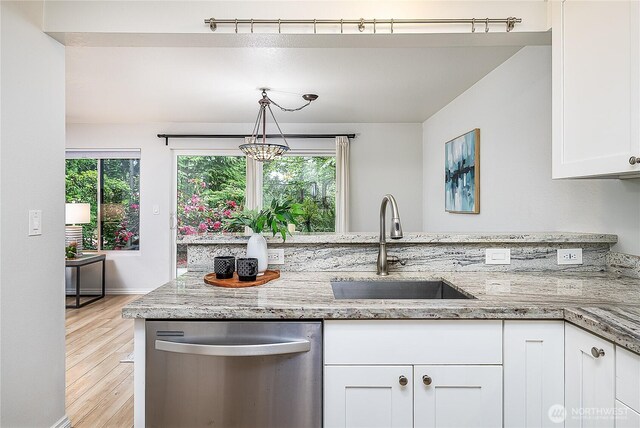 kitchen featuring dishwasher, a sink, white cabinets, light wood finished floors, and light stone countertops