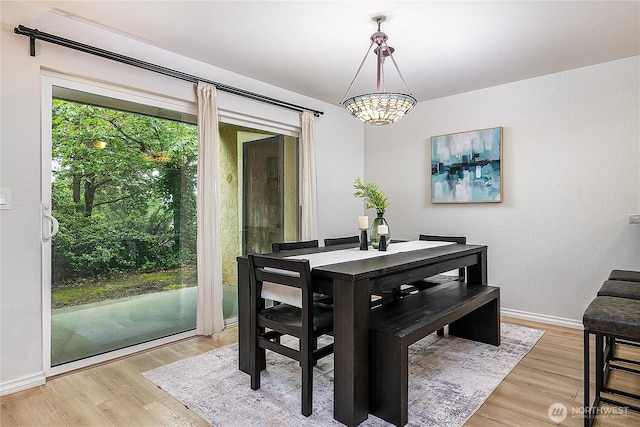 dining space with light wood-style floors, a chandelier, and baseboards