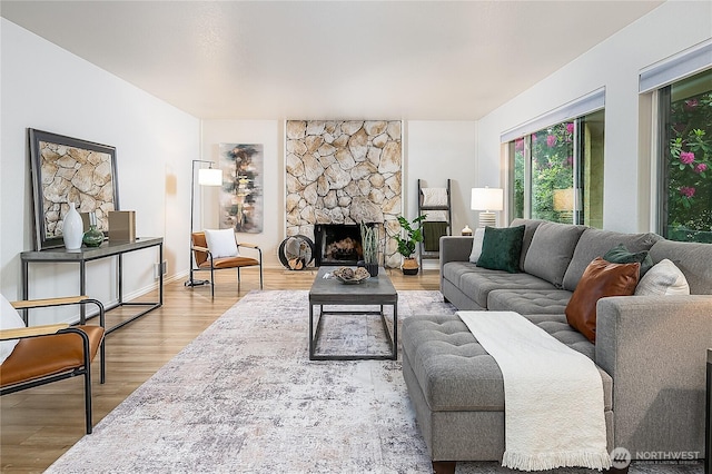 living room with wood finished floors and a stone fireplace
