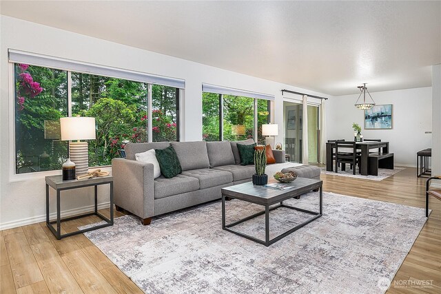 living room featuring baseboards, light wood-type flooring, and a chandelier