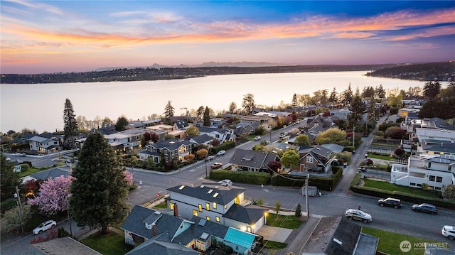 aerial view at dusk featuring a water view and a residential view
