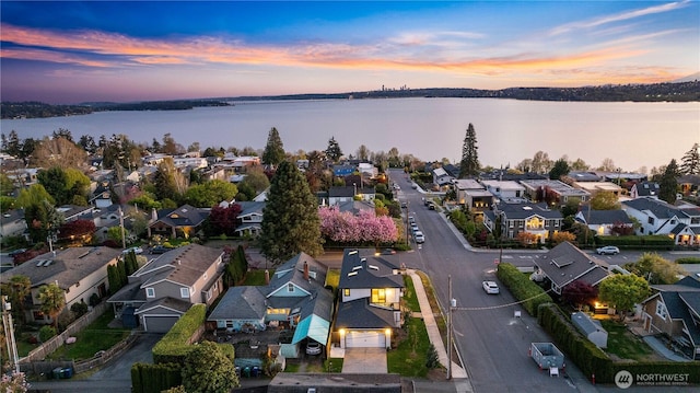 aerial view at dusk with a residential view and a water view