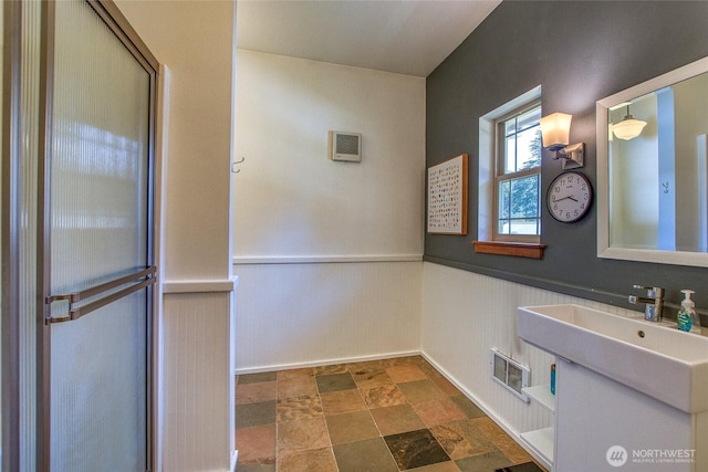 bathroom with visible vents, wainscoting, and stone finish flooring