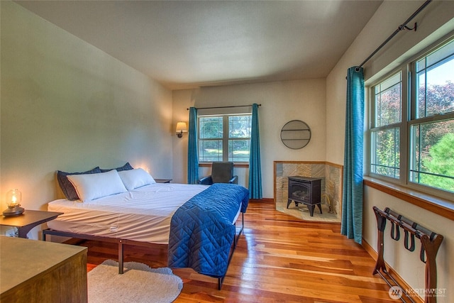 bedroom featuring a wood stove and wood finished floors