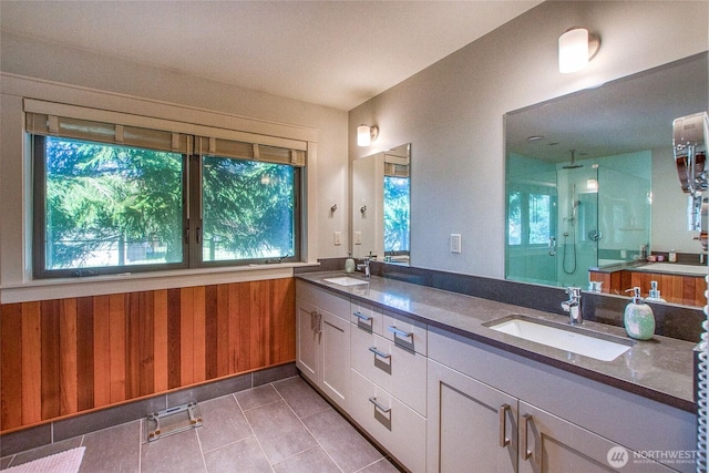 full bath featuring a sink, tile patterned floors, a stall shower, and wooden walls