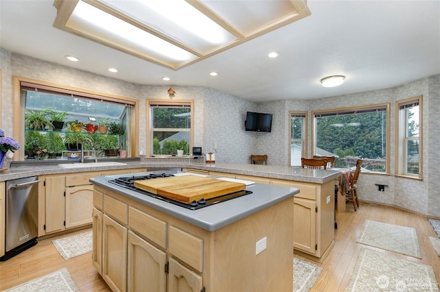 kitchen with light wood-type flooring, a kitchen island, dishwasher, wallpapered walls, and light brown cabinets