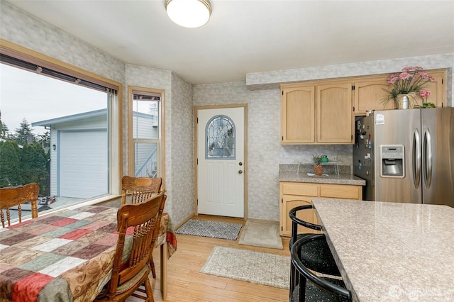 kitchen with stainless steel refrigerator with ice dispenser, light wood-type flooring, wallpapered walls, and light brown cabinetry