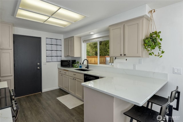 kitchen with a kitchen breakfast bar, a sink, black appliances, a peninsula, and dark wood-style floors