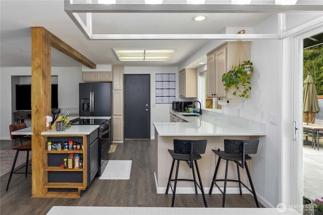 kitchen featuring dark wood-style flooring, a sink, light countertops, a peninsula, and black appliances