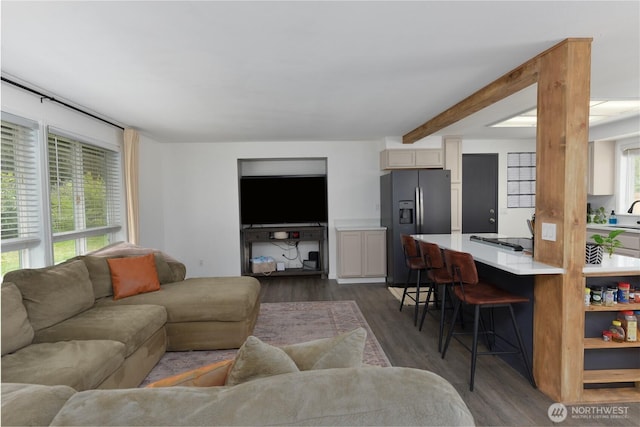 living area featuring beam ceiling and dark wood-style floors