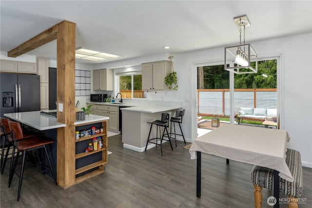 kitchen with a breakfast bar, a sink, light countertops, dark wood finished floors, and black appliances