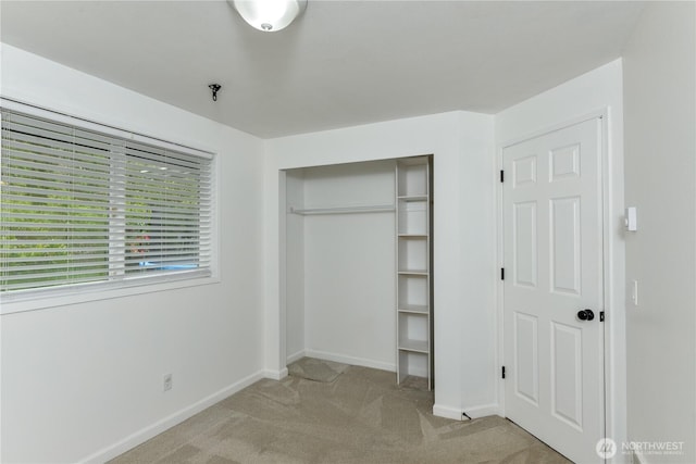 unfurnished bedroom with carpet floors, baseboards, and a closet