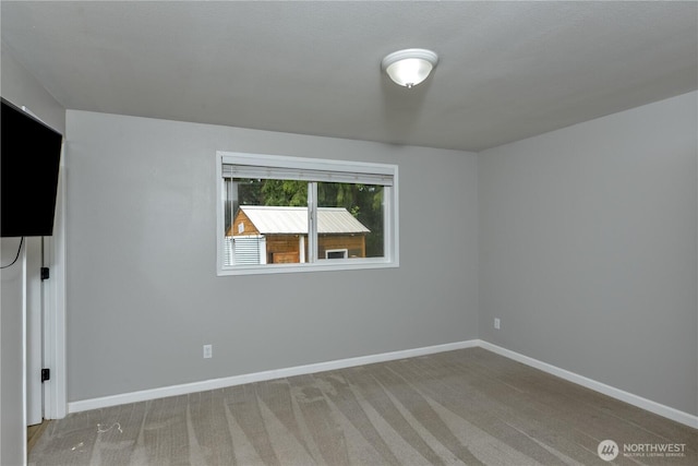carpeted spare room featuring baseboards