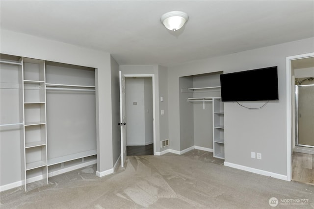 unfurnished bedroom featuring two closets, carpet flooring, and baseboards