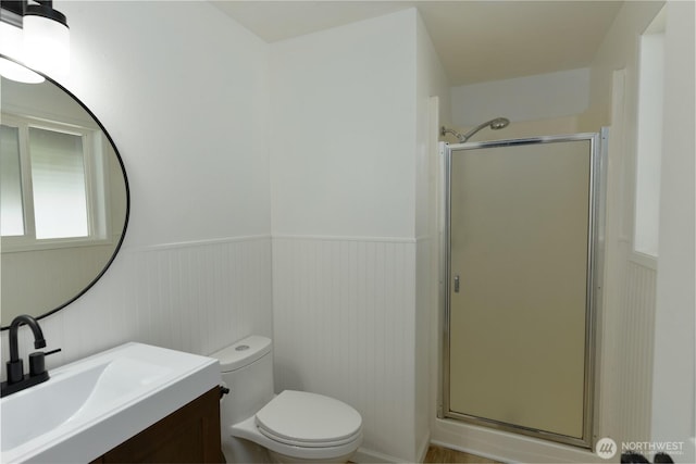 full bathroom with vanity, a wainscoted wall, a shower stall, and toilet