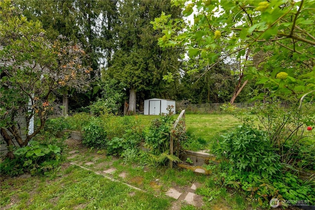view of yard with an outbuilding, fence, and a storage shed