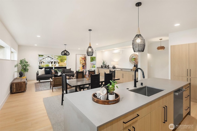 kitchen featuring modern cabinets, a spacious island, light wood finished floors, a sink, and light brown cabinetry