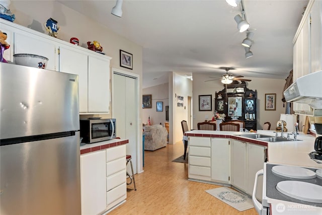 kitchen with white cabinets, ceiling fan, appliances with stainless steel finishes, tile counters, and a peninsula