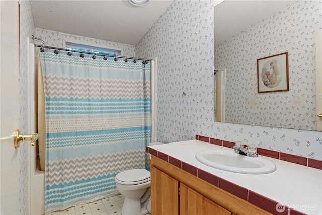 bathroom with vanity, toilet, wallpapered walls, and a textured ceiling