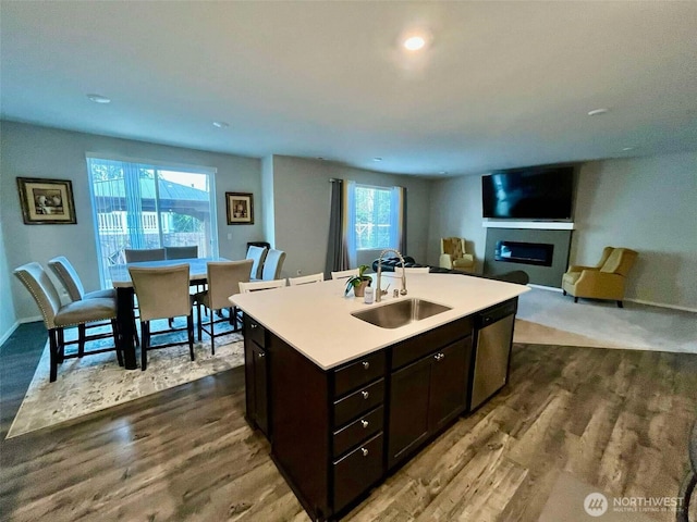 kitchen with a fireplace, dark wood-type flooring, a healthy amount of sunlight, dishwasher, and a sink