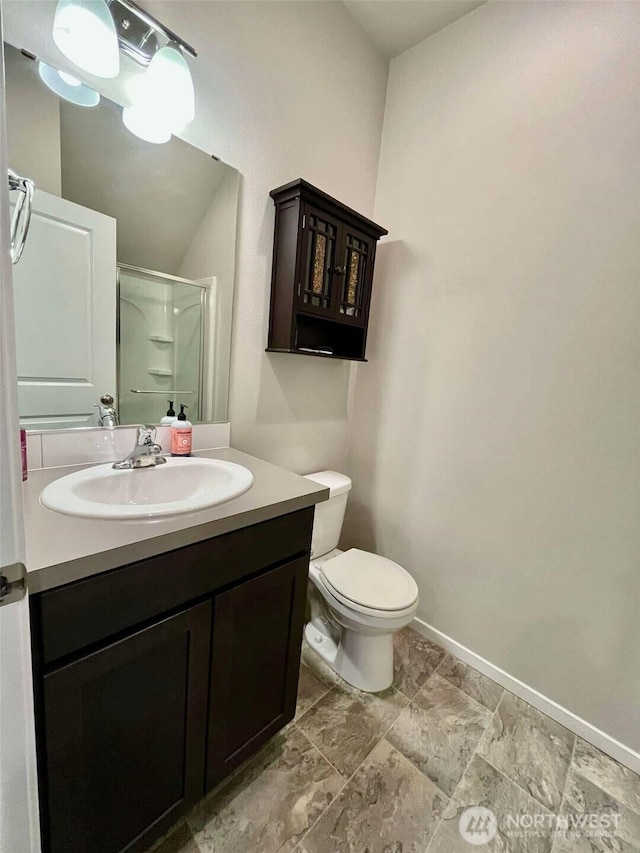 full bath with a shower stall, vanity, baseboards, and toilet