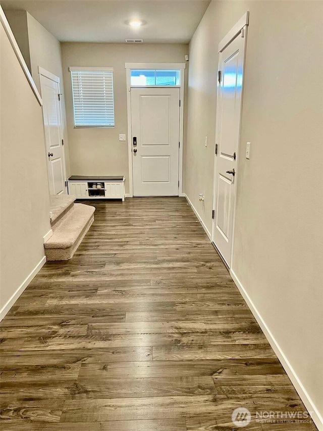 doorway to outside with dark wood-style floors, baseboards, and visible vents
