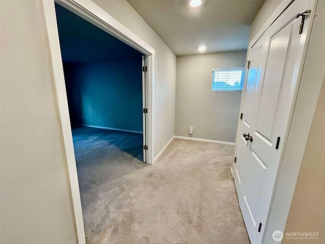 corridor featuring baseboards, recessed lighting, and light colored carpet