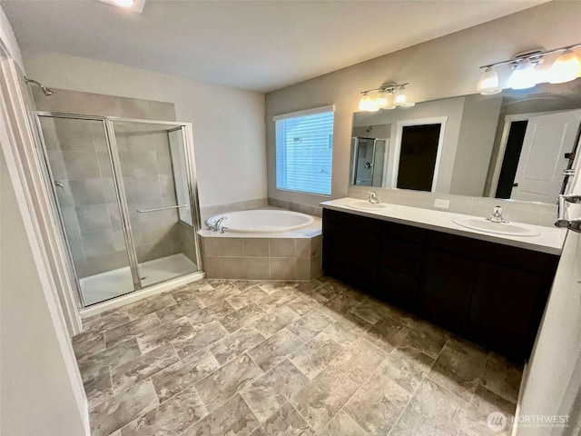 bathroom featuring a shower stall, double vanity, a bath, and a sink