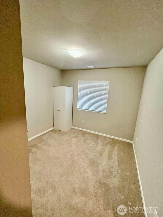 carpeted spare room featuring visible vents and baseboards