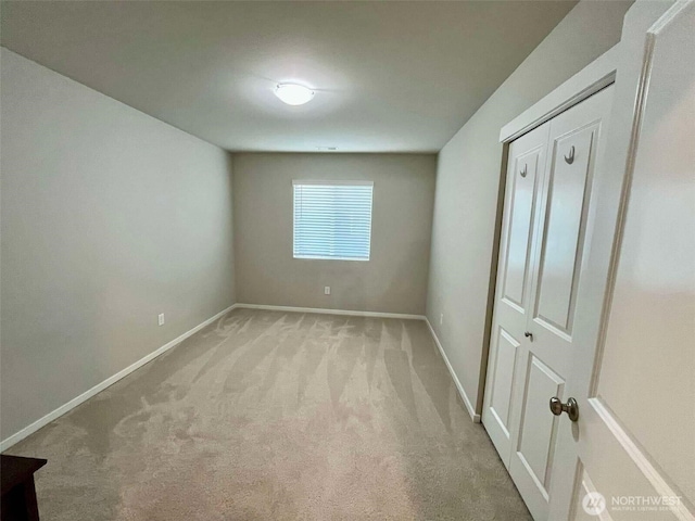 unfurnished bedroom with a closet, baseboards, and light carpet