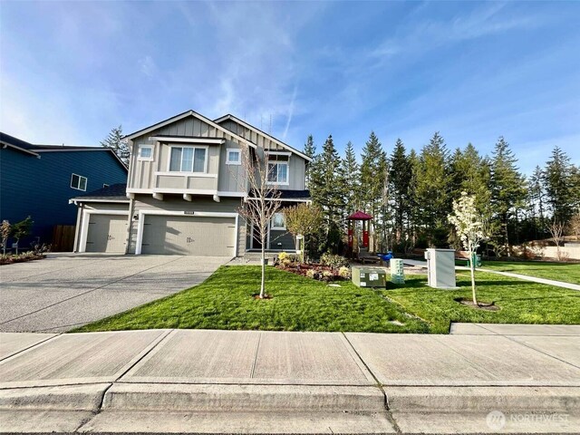 view of front of property with concrete driveway, a front yard, board and batten siding, and an attached garage