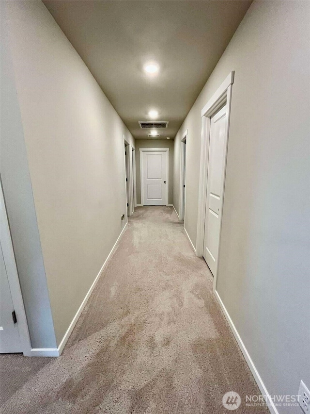 hallway with visible vents, baseboards, and carpet floors