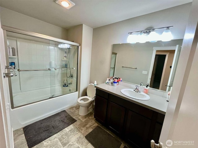 bathroom featuring toilet, vanity, and shower / bath combination with glass door