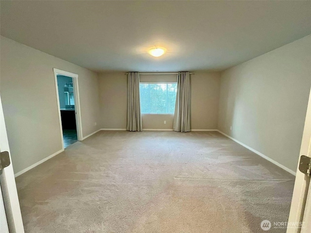 unfurnished room with baseboards and light carpet