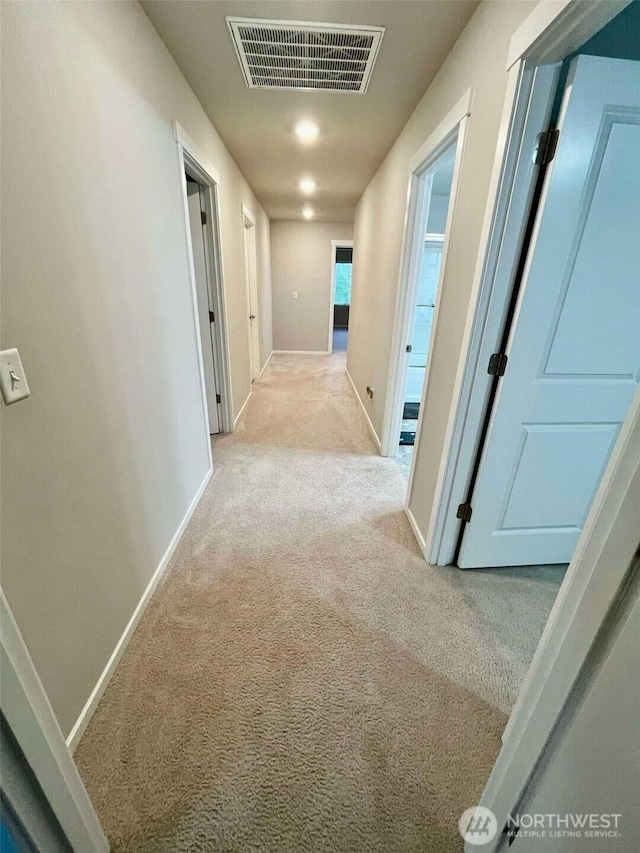 hallway with baseboards, carpet, and visible vents