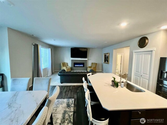 dining area featuring dark wood-style floors, a glass covered fireplace, and recessed lighting