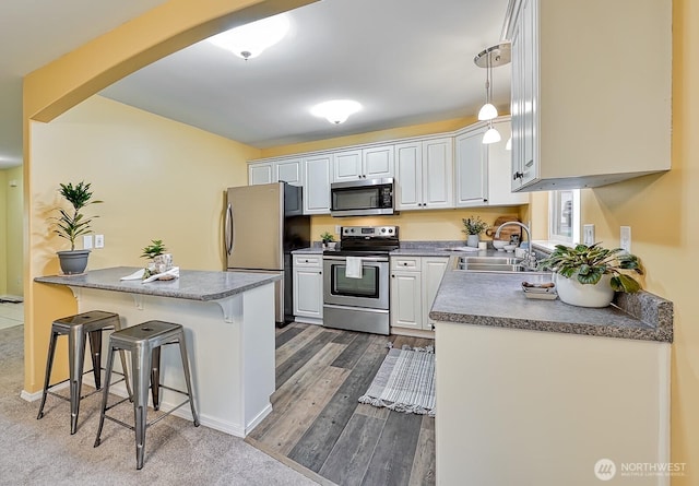 5786 Skagit Pl, Blaine, WA 98230 - kitchen with dark wood finished floors, a breakfast bar, appliances with stainless steel finishes, dark countertops, and a sink