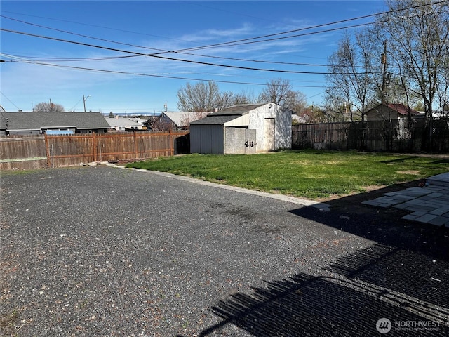 view of yard with an outdoor structure, a shed, and a fenced backyard
