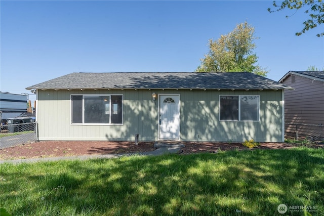ranch-style house with a front yard, roof with shingles, and fence
